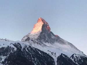 The summit of a snow-covered mountain with the sun hitting it