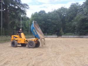 A dump truck constructing the arena made of Eqivia equestrian surface