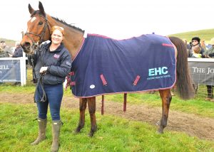 A woman holding a horse wearing an Equine Healh Centre cover